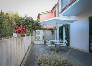 une terrasse avec une table et un parasol dans l'établissement Appartamento nuovissimo con parcheggio gratuito, à Massa