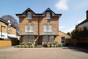 a brick house with a driveway in front of it at Teddington Lodge in Teddington