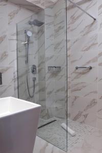 baño con ducha y puerta de cristal en Hotel McPietroasa, en Haleş
