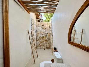 La salle de bains est pourvue de toilettes et d'un mur en pierre. dans l'établissement Rumah Canaria Bungalow, à Gili Trawangan