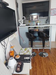 ein Wohnzimmer mit einem Schreibtisch, einem TV und Stühlen in der Unterkunft Art studio Marina Cape-private host in Rawda