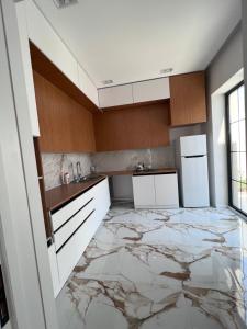 eine Küche mit Marmorböden und weißen Schränken in der Unterkunft Villa boho in Baku