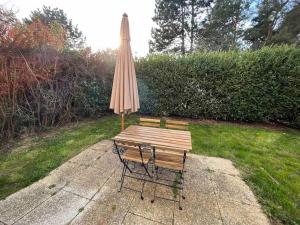 een tafel met een paraplu en een stoel en een tafel met een bank bij Hana Home T2 Spacieux avec jardin privatif in Montigny-le-Bretonneux