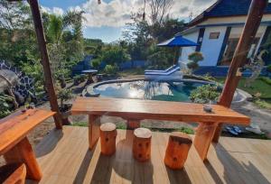 einen Holztisch und Hocker auf einer Terrasse mit einem Pool in der Unterkunft Batur Happy House in Kintamani
