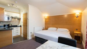 a bedroom with a large white bed and a kitchen at Teddington Lodge in Teddington