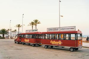 a red trolley car parked in a parking lot at Apartamento Mar y Arena in Cullera