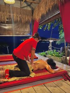 a woman laying down on a blanket while a man is working at The Beach Cafe in Ko Chang