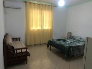 a bedroom with a bed and a chair and a window at Vila Demo in Vlorë