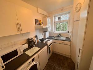 a small kitchen with white cabinets and a sink at Neasden, Dollis Hill London Apartment in London