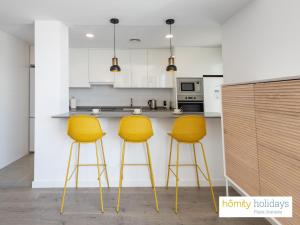 a kitchen with two yellow bar stools in front of a counter at Homity Holidays - Playa Granada - Aguacate Beach in Motril