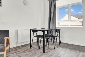 a black table and chairs in a room with a window at Serviced accomodation - For Families or Corporate in London