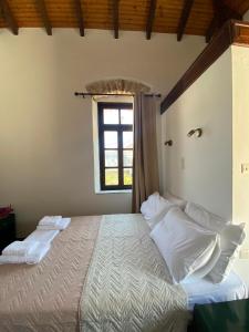 um quarto com uma cama com almofadas brancas e uma janela em Belessi's Mansion em Yéfira