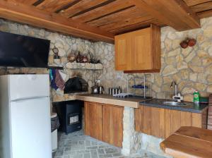 a kitchen with wooden cabinets and a stone wall at Терасите - Къща 2 in Ribarica
