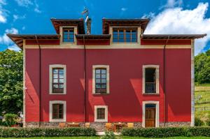 Piloña的住宿－Casona de Indias，一座红色的建筑,上面有旗帜
