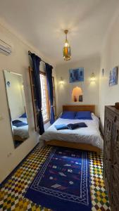 een slaapkamer met een bed, een spiegel en een tapijt bij DAR SEFFAH au cœur de la Médina in Fès