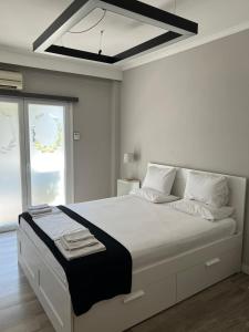 ein weißes Schlafzimmer mit einem großen weißen Bett und einem Fenster in der Unterkunft Chic & Cozy Apartment in Thessaloniki