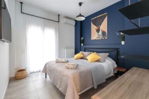 Schlafzimmer mit blauen Wänden und einem Bett mit gelben Kissen in der Unterkunft Home Cinema at the center of Thessaloniki in Thessaloniki