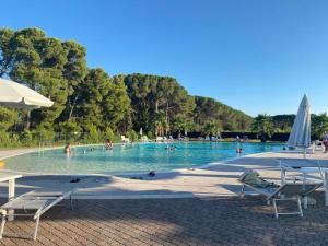 a swimming pool with chairs and people in the water at Interno H10 - Olimpia Residence in Policoro