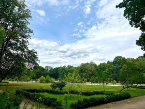 um parque com um campo verde e árvores ao fundo em K22 Park Lazienki Aparts in Warsaw em Varsóvia