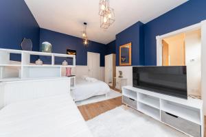 a bedroom with blue walls and a large flat screen tv at Free Parking Guaranteed Weekly & Monthly Stay Savings Close to Reading Station in Reading