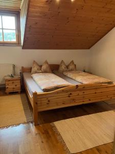 uma grande cama de madeira num quarto com tecto de madeira em Ferienwohnung Auersbergsreut em Haidmühle