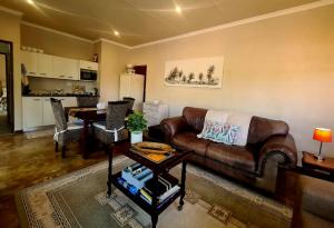 a living room with a leather couch and a table at Firefly Cottage: Cosi nest tucked away in garden in Kenton on Sea