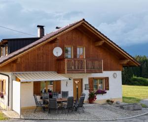a house with a balcony and a table and chairs at Ferienwohnung Auersbergsreut in Haidmühle