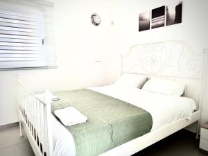 1 cama blanca en un dormitorio blanco con cuna blanca en Vacation Apartment by The Sea - Achziv, en Nahariyya