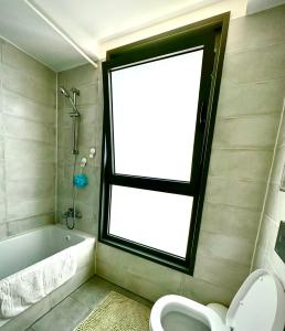 Vacation Apartment by The Sea - Achziv في نهاريا: حمام مع نافذة وحوض استحمام ومرحاض