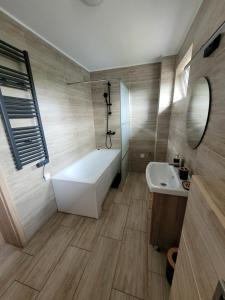 a bathroom with a white tub and a sink at BŁĘKITNA apartamenty in Kołobrzeg