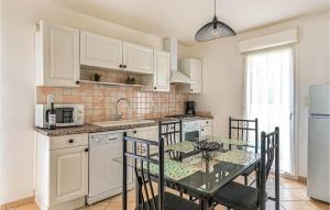 eine Küche mit weißen Schränken und einem Tisch mit Stühlen in der Unterkunft Stunning Home In Beauville With Kitchen in Beauville