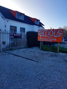 a house with a sign in front of a fence at Keedols Inn & Backpackers in Knysna