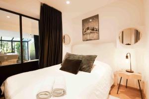 a bedroom with a white bed and a mirror at Golfe de St Tropez 3 pièces jardin piscine privée in Sainte-Maxime