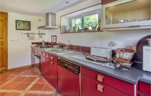 a kitchen with red cabinets and a sink at Cozy Home In Augignac in Augignac +15 photos