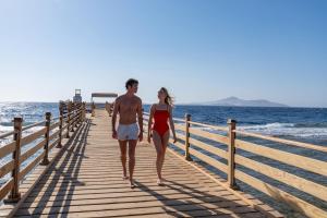 a man and a woman walking down a wooden pier at Cleopatra Luxury Resort Sharm El Sheikh in Sharm El Sheikh