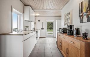 uma cozinha com armários brancos e piso em azulejo em Nice Home In Vesls With 2 Bedrooms And Wifi em Øsløs