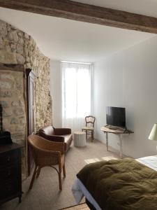 Un Petit Château في Lauzun: غرفة نوم بسرير وكرسي وتلفزيون