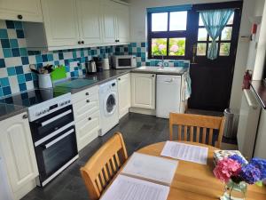 a kitchen with white cabinets and a wooden table at Long Linhay Mortehoe Woolacombe in Woolacombe