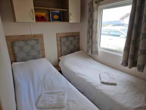Duas camas num pequeno quarto com uma janela em End of the road Farm-Cabin em Búðardalur