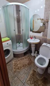 a bathroom with a toilet and a sink and a washing machine at 1 к квартира в Центре Мухита д 128 in Uralsk