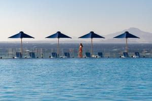 a woman walking on the edge of a pool with umbrellas at Cleopatra Luxury Resort Sharm El Sheikh in Sharm El Sheikh