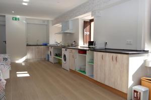 eine große Küche mit weißen Geräten und Holzböden in der Unterkunft Albergue Gares in Puente la Reina