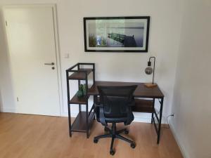 einen Schreibtisch mit einem Stuhl und einem Bild an der Wand in der Unterkunft Spacious 70sqm apt in popular location in Düsseldorf