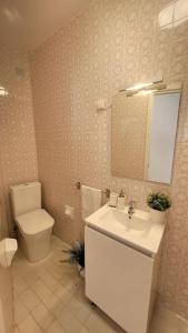 een badkamer met een wastafel, een toilet en een spiegel bij Piso con vistas al mar. Apartamento Miramar in San Cibrao