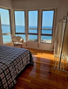 een slaapkamer met een bed en uitzicht op de oceaan bij Piso con vistas al mar. Apartamento Miramar in San Cibrao
