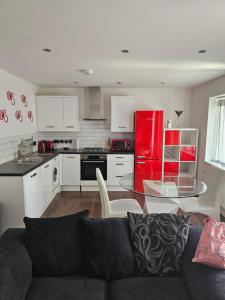 een woonkamer met een bank en een rode koelkast bij Chi's apartment in Barking