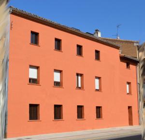 ein orangefarbenes Gebäude mit Seitenfenstern in der Unterkunft Albergue Gares in Puente la Reina