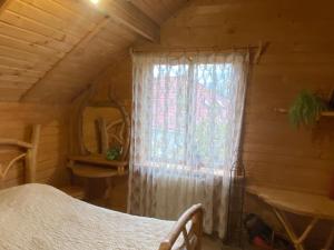 a bedroom with a window in a log cabin at Oselia Mandrivnykiv in Tukhlya