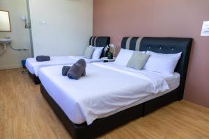 2 camas en una habitación con sábanas y almohadas blancas en FAMILIA INN, en Kangar
