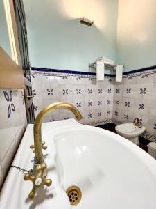 カルモナにあるHotel Serviliaのバスルーム(白い洗面台、金の蛇口付)